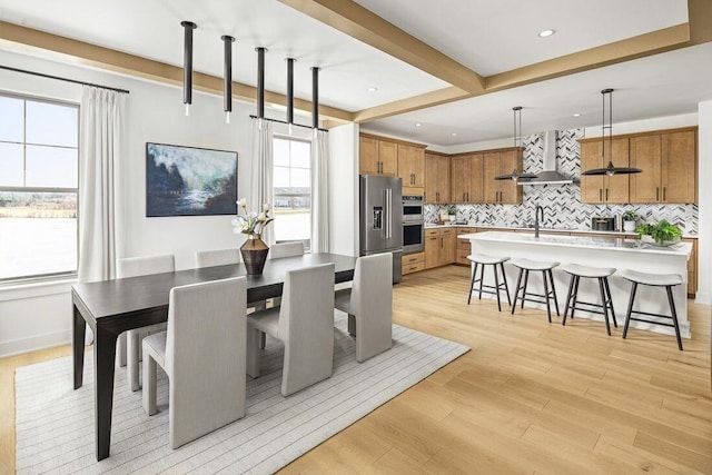 dining room with beam ceiling, recessed lighting, baseboards, and light wood finished floors