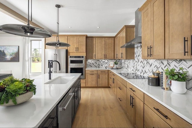 kitchen featuring a sink, wall chimney range hood, tasteful backsplash, stainless steel appliances, and light countertops