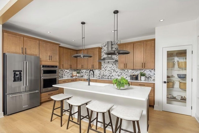 kitchen with appliances with stainless steel finishes, brown cabinetry, and light countertops