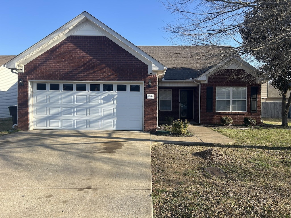 ranch-style house featuring brick siding, an attached garage, a shingled roof, a front lawn, and driveway