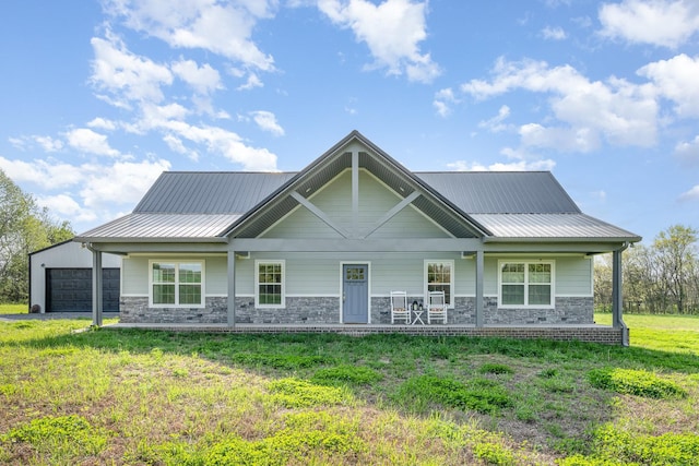view of front facade featuring a garage, a front yard, metal roof, and stone siding