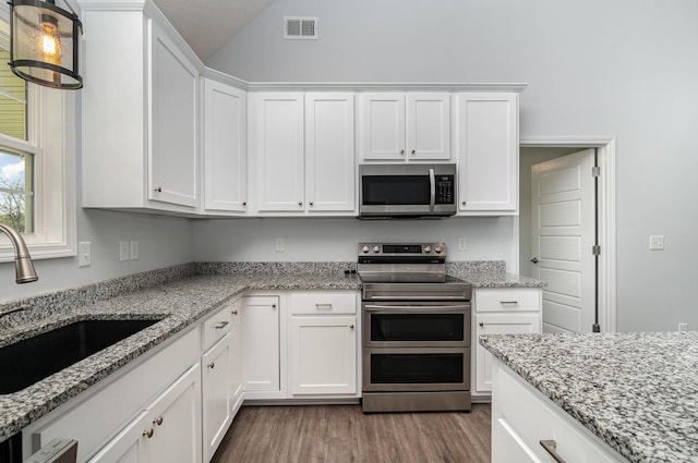 kitchen with white cabinetry, visible vents, stainless steel appliances, a sink, and wood finished floors