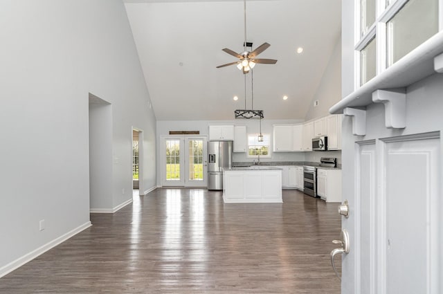 unfurnished living room with high vaulted ceiling, dark wood finished floors, baseboards, and ceiling fan