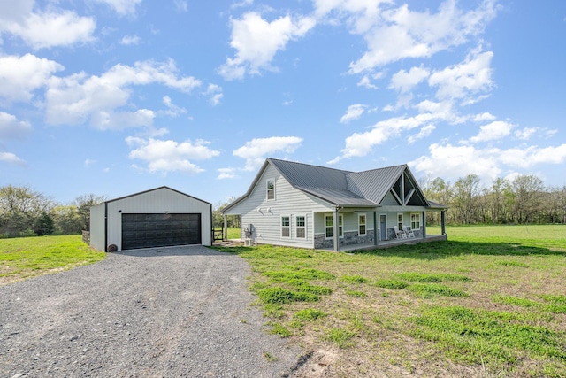 view of side of property with a yard, a porch, metal roof, a garage, and an outbuilding