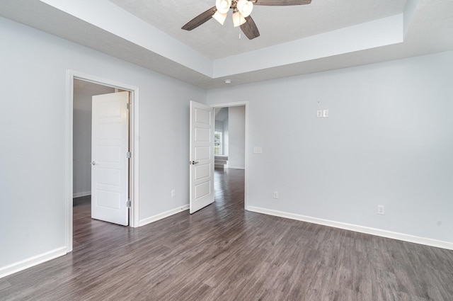 empty room with dark wood-type flooring, baseboards, and a ceiling fan