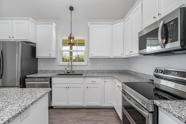 kitchen with a sink, appliances with stainless steel finishes, white cabinetry, and dark wood finished floors