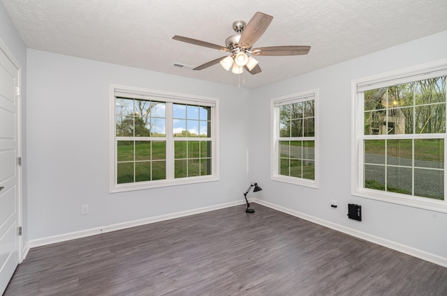 empty room featuring visible vents, baseboards, ceiling fan, a textured ceiling, and dark wood-type flooring