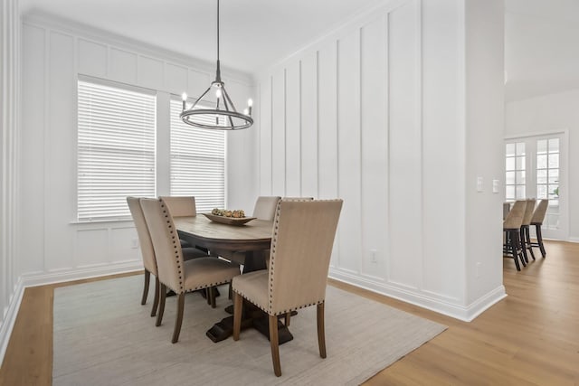 dining space featuring a notable chandelier, a decorative wall, and light wood-style floors