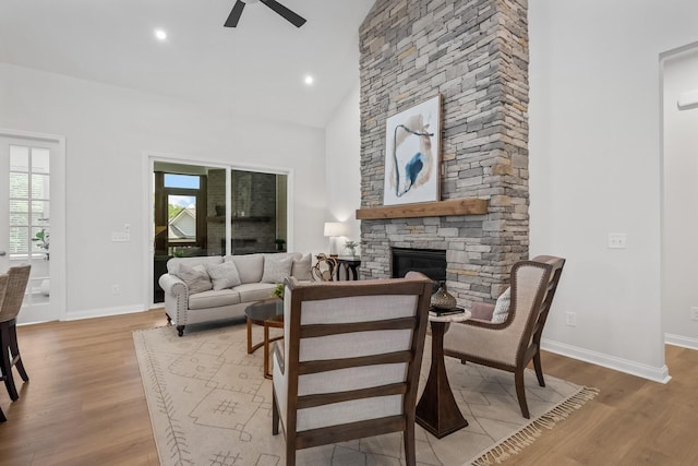 living area featuring a fireplace, high vaulted ceiling, a ceiling fan, and wood finished floors