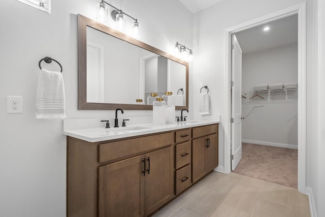 bathroom featuring double vanity, tile patterned flooring, a spacious closet, and a sink