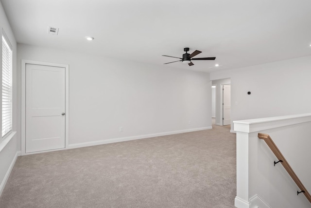 spare room featuring light carpet, visible vents, baseboards, and ceiling fan