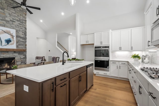 kitchen featuring light countertops, light wood-type flooring, appliances with stainless steel finishes, white cabinets, and a sink