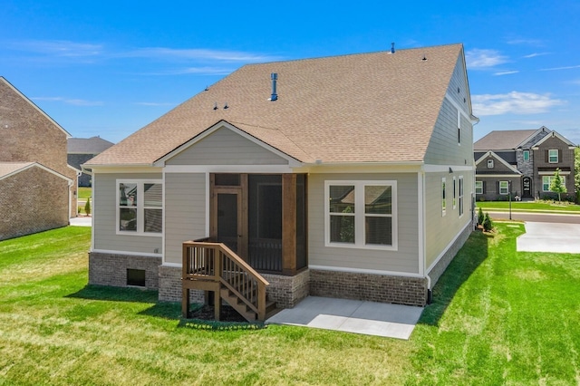 back of property with a lawn, a sunroom, and a shingled roof