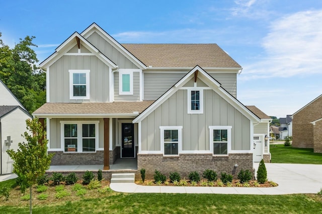 craftsman inspired home with brick siding, board and batten siding, a shingled roof, covered porch, and driveway