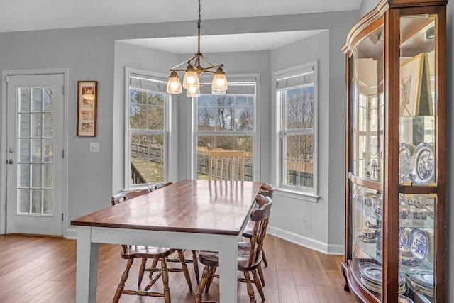 dining space featuring a notable chandelier, baseboards, and wood finished floors