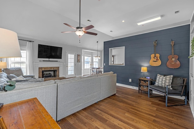 living area featuring baseboards, ceiling fan, vaulted ceiling, a fireplace, and wood finished floors