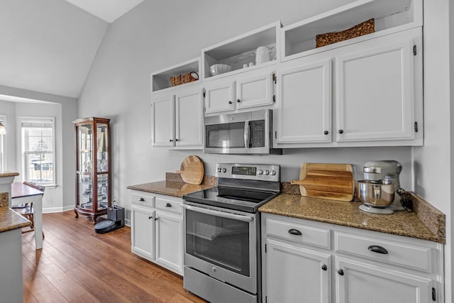 kitchen with wood finished floors, open shelves, vaulted ceiling, appliances with stainless steel finishes, and white cabinetry