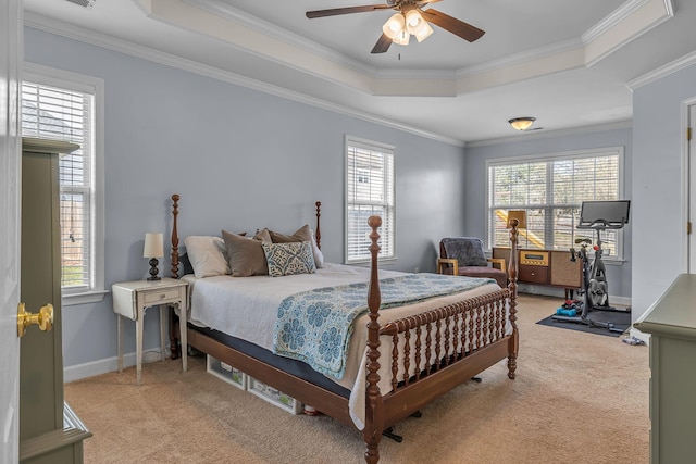 bedroom with a tray ceiling, crown molding, baseboards, and light carpet