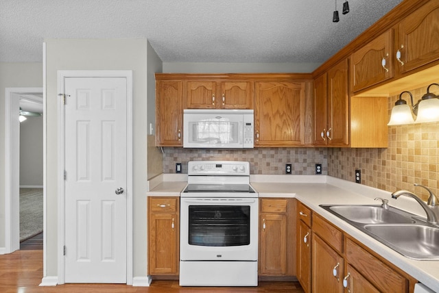 kitchen featuring a sink, white appliances, and brown cabinets