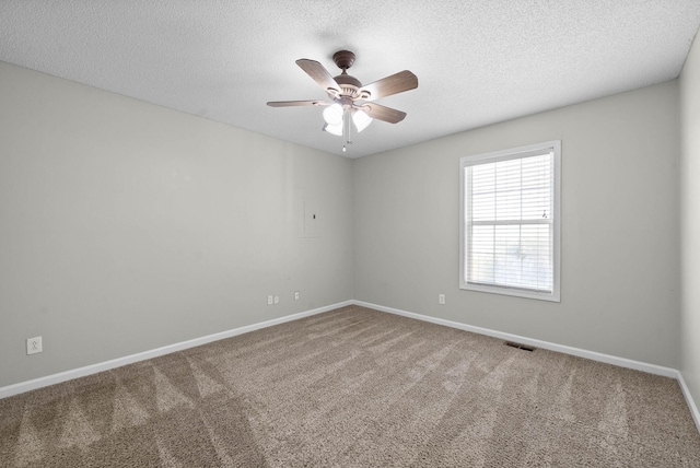 carpeted empty room with visible vents, baseboards, a textured ceiling, and a ceiling fan