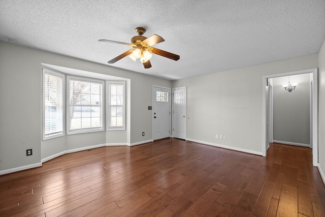 interior space with dark wood finished floors, ceiling fan with notable chandelier, and baseboards