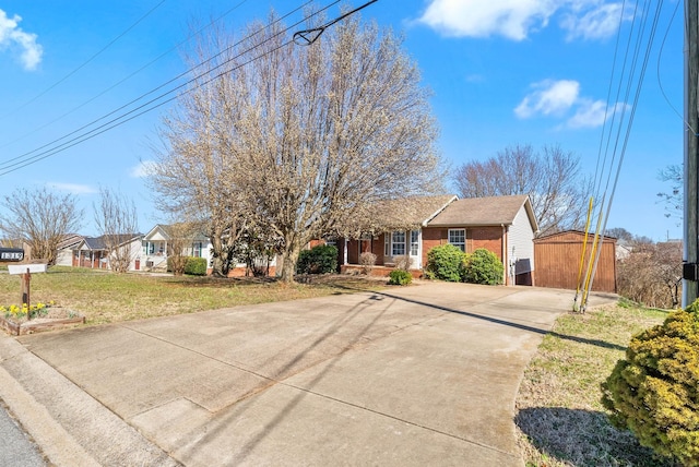 single story home with an outdoor structure, brick siding, a front lawn, and driveway