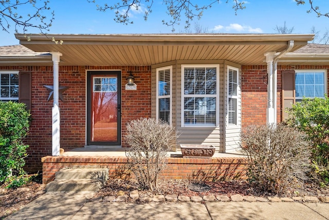 doorway to property featuring covered porch and brick siding