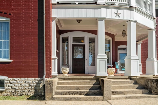 entrance to property featuring brick siding and covered porch