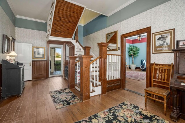 entrance foyer with stairway, hardwood / wood-style flooring, crown molding, and wallpapered walls