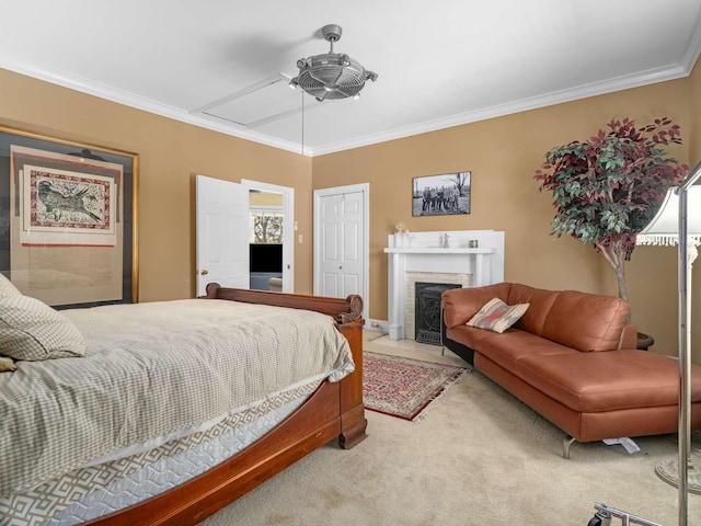 bedroom with crown molding, ceiling fan, light colored carpet, a fireplace, and a closet