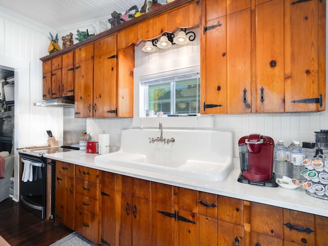 kitchen with under cabinet range hood, brown cabinets, black range with electric cooktop, and a sink