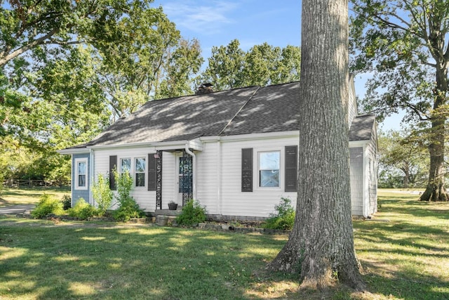 view of front of property with a chimney, a front lawn, and roof with shingles