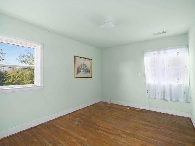 unfurnished room featuring wood finished floors, visible vents, and baseboards