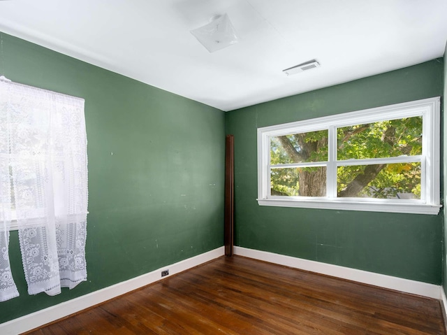 unfurnished room with wood finished floors, baseboards, and visible vents