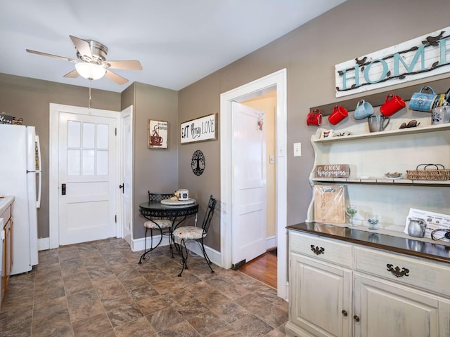 kitchen featuring baseboards, ceiling fan, freestanding refrigerator, white cabinetry, and open shelves