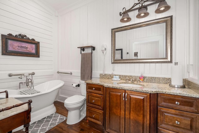 bathroom with a freestanding bath, ornamental molding, toilet, vanity, and wood finished floors