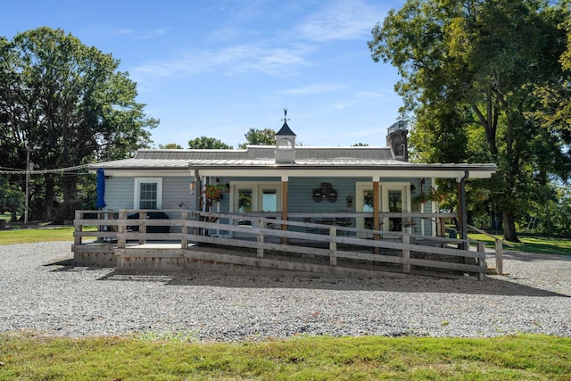 view of front of house with french doors, a chimney, and metal roof