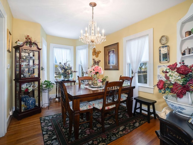 dining space with a chandelier, baseboards, and wood finished floors