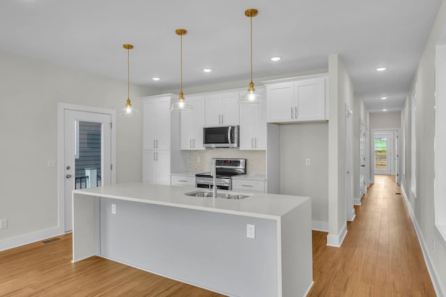 kitchen featuring decorative backsplash, white cabinets, light wood finished floors, and appliances with stainless steel finishes