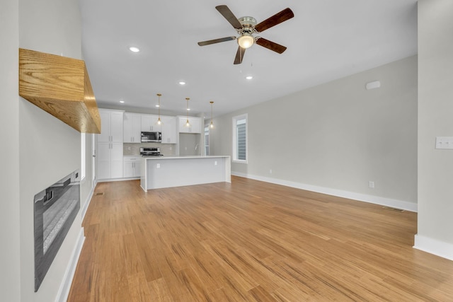 unfurnished living room featuring recessed lighting, light wood-style flooring, baseboards, and ceiling fan