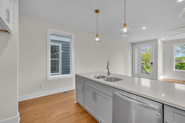 kitchen featuring light wood finished floors, visible vents, light countertops, stainless steel dishwasher, and a sink