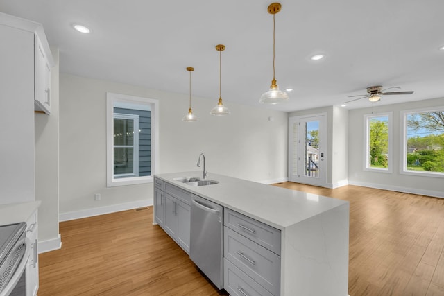 kitchen with light wood finished floors, appliances with stainless steel finishes, light countertops, and a sink