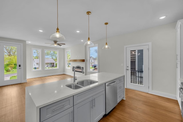 kitchen with ceiling fan, a sink, light wood-style floors, pendant lighting, and stainless steel dishwasher