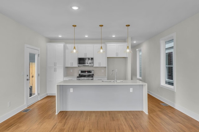 kitchen with white cabinetry, stainless steel appliances, light countertops, and a sink