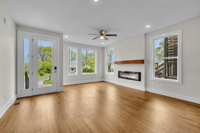 unfurnished living room featuring visible vents, recessed lighting, wood finished floors, a glass covered fireplace, and a ceiling fan