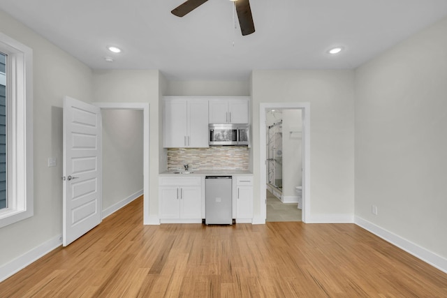 kitchen with tasteful backsplash, light wood-style floors, stainless steel appliances, a ceiling fan, and a sink