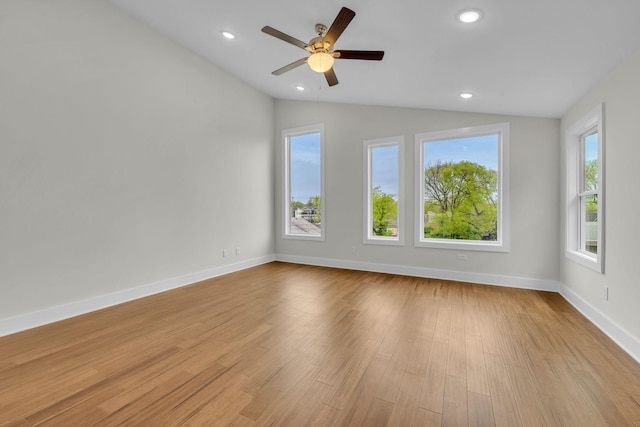 spare room featuring light wood finished floors, plenty of natural light, recessed lighting, and lofted ceiling