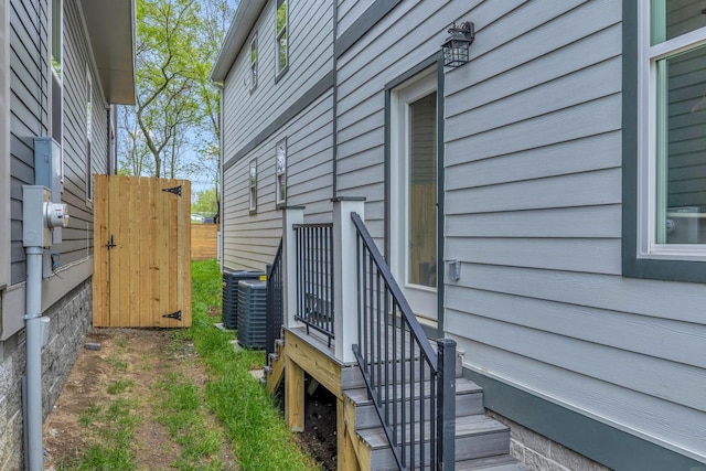 view of property exterior with central air condition unit and a gate