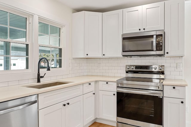 kitchen with decorative backsplash, stainless steel appliances, light countertops, and a sink