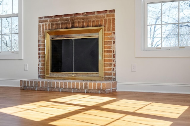 interior details with baseboards, a brick fireplace, and wood finished floors